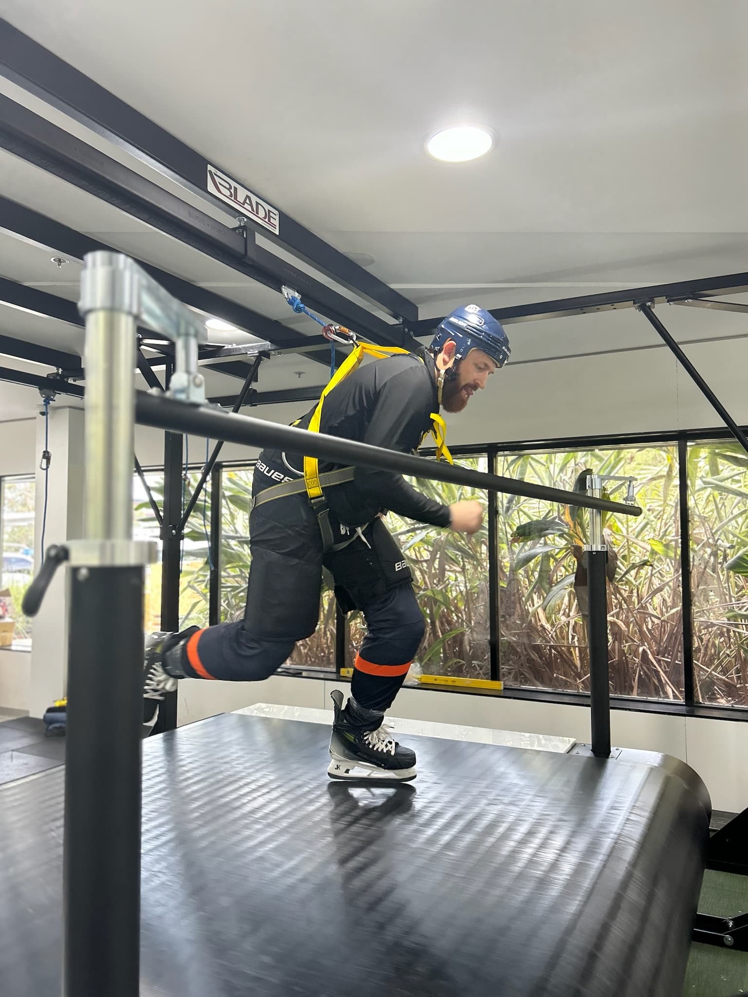 Skater in full gear striding on the Woodway Blade Treadmill in a harness